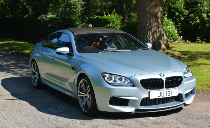 Just bought an M6 Gran Coupe - Page 32 - M Power - PistonHeads UK - The image shows a silver BMW car parked on a grassy area. It is an open-top sports car with customizations, including aftermarket wheels and exhaust system. The car has a sleek design with aerodynamic body parts. The background suggests a suburban setting with trees and a clear sky visible in the distance.