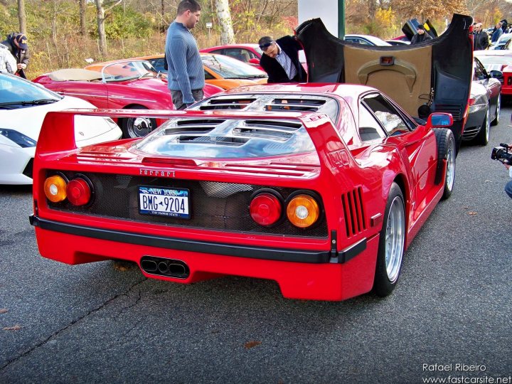 Supercars Rarities Spotted Pistonheads - The image depicts a vibrant scene on the street where a group of people, including those using crutches and helmets, are gathered around red and black Ferrari sports cars. One car, parked sideways, has its doors open, presumably to display the interior or for photo opportunities. The cars have visible license plates and are equipped with high-performance brakes, indicating their status as sports cars. The tranquil atmosphere is contrasted with the presence of multiple individuals interested in these impressive machines.