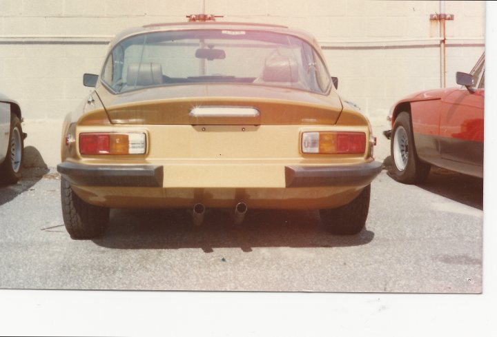 Last 3000S exports to US? - Page 1 - Classics - PistonHeads - The image shows an old Datsun car in a parking lot. The car appears to be a convertible, characterized by its rear licence plate, and is parked nose-on to the viewer. It has a distinctive orange-beige paint scheme. Behind the Datsun, there is another car, partially visible, and in the background, a white wall, giving the impression that the setting might be a maintenance area. The vehicle's license plate is visible, and it's a cloudy day.