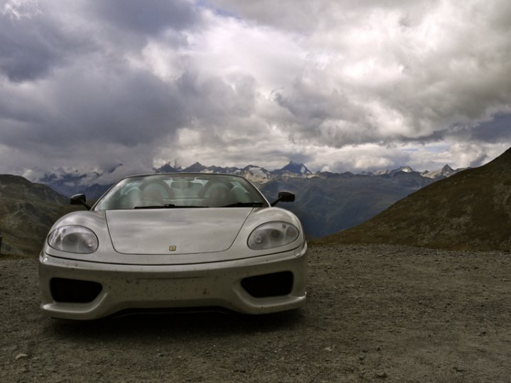 360 thread - Page 1 - Ferrari V8 - PistonHeads - The image portrays a luxury sports car parked on a mountain peak. The car, a silver Lamborghini model identified by the badge on the front, is situated on a rocky path. The backdrop features a dramatic sky filled with clouds, indicating possible changeable weather, and a mountainous terrain suggesting a remote location. The car is alone, adding a sense of tranquility to the scene.