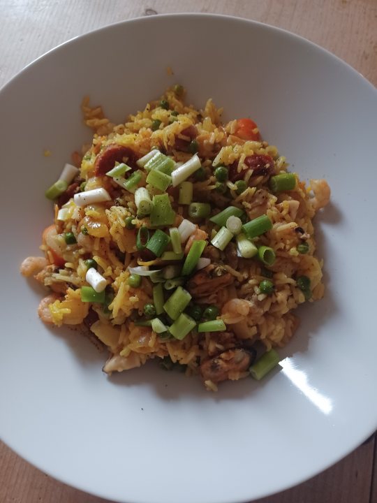 Pistonheads - The image showcases a delicious-looking plate of food placed on a dining table. The plate is filled with a meal that consists of rice, chicken, and a variety of vegetables including carrots and broccoli. The dish appears to be garnished with chopped green onions, adding a pop of color to the otherwise monochrome palette of the meal.