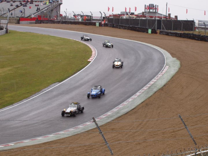 BRSCC Meeting Brands Hatch 11-06-2011 - Page 1 - UK Club Motorsport - PistonHeads - The image captures an intense scene from a motorsport race. A four-car train is in the lead, with the open wheel cars racing head-to-head. The cars are close to the track edge, suggesting a thrilling battle for the lead. In the background, a large audience is watching from the corners of the track, adding to the high-stakes atmosphere of the race. The sky overhead is cloudy, hinting at dramatic weather conditions that could impact the race.