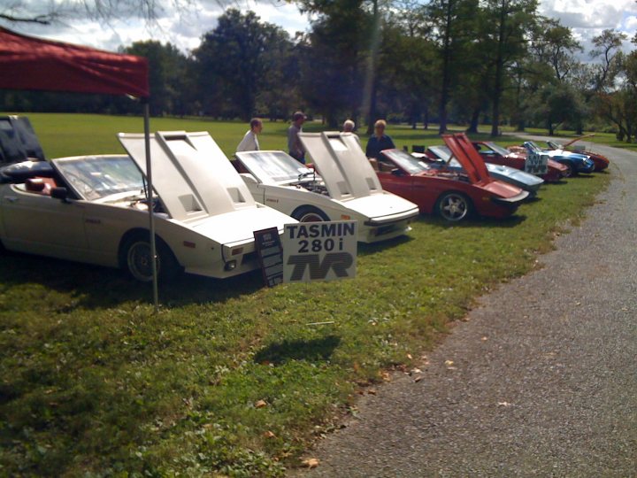 Road Pistonheads Youve Rarest Year - The image captures a group of vintage cars parked side by side on grass alongside a road. They appear to be part of a car show or exhibition. The cars are white, red, and blue, showcasing a variety of models and designs. One eye-catching detail is that the hoods of several cars are propped open, revealing the engine compartments. The grass under the cars is predominantly green, suggesting that the event is taking place during a season when plants are in full growth. The setting is outdoors during what seems to be daytime. The cars add a splash of color against the more natural shades of the grass and road.