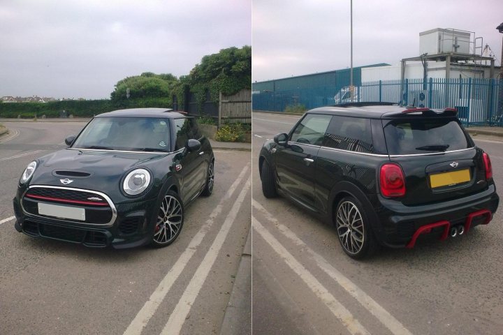 F56 John Cooper Works - Page 1 - Readers' Cars - PistonHeads - The image is a composite of two separate photos, both featuring the same car parked in different locations. On the left, the car is parked on a street with a building and a blue sky in the background. It's a black Mini Cooper convertible with a distinctive red stripe running down the middle. On the right, the car is parked in front of a blue fence, showcasing its sporty stance with black wheels and a red stripe accentuating its design. The license plate is visible in both images.