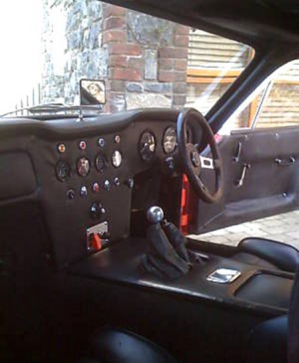 Early TVR Pictures - Page 110 - Classics - PistonHeads - This is a close-up image of the interior of a car, showing the driver's side with the steering wheel on the right. The steering wheel features many buttons and knobs, likely for the vehicle's radio or additional controls. On the door areas, there are one-way mirror attachments. The dashboard and the gear shifter are visible, suggesting a manual transmission vehicle. The passenger seat is in view, and the general style of the vehicle is reminiscent of classic or racing cars.