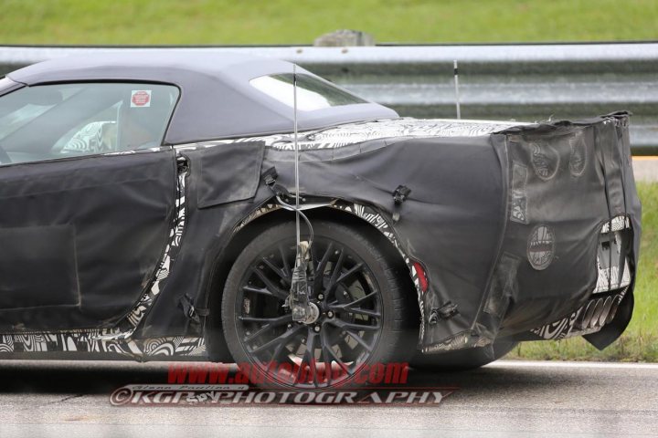 C7 Z0? Mule - Page 1 - Corvettes - PistonHeads - The image is a photograph of a race car taken during daylight hours. The car is predominantly black and silver with visible pinstripe designs. Its bodywork has significant areas covered with what appears to be protective plastic or tape, particularly around the rear fenders and quarter panels. This protective material is likely used to mask paint or finalize race preparations. The tire is large with a distinctive sidewall design that includes a pattern and a logo, resembling products from Goodyear or Firestone, which are known to be standard fitments for racing cars. The protective tape is inscribed with red text, presumably for identification purposes, and includes a watermark or logo as well. There are no visible texts indicating the model or make of the vehicle, but given the context and features visible in the photograph, it is highly likely that this car is a NASCAR or similar racing car.