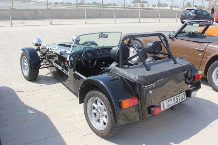 Middle East spotted thread - Page 35 - Middle East - PistonHeads - The image showcases a vintage black sports car parked on a beige tiled floor. It's a close-up of the rear and side of the vehicle, with a distinct dual-exhaust system visible. The car features a convertible top that's currently down, and the license plate reads EU 19V. In the background, you can see other cars parked, suggesting this is at a public parking area or showroom.