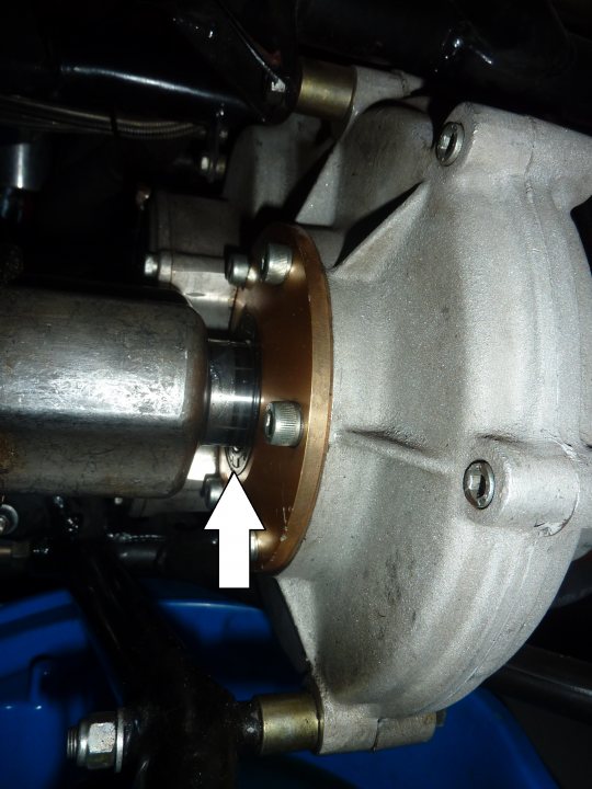 Oil leak from Differential Gear drive unit/ Driveshaft? - Page 1 - Radical - PistonHeads - The image is a close-up photograph of a mechanical component, specifically a carburetor. This particular model appears to be a radial flow four-stroke engine carburetor, characterized by its bell-like shape with a flanged protrusion pointing towards the bottom of the frame. There is a clear plastic arrow pointing to the right side of the image, indicating the direction of an unseen cable or wire. The surrounding environment looks industrial and utilitarian with metallic components and blue plastics around the carburetor, possibly within an engine compartment. The photo seems to be taken with a focus on the carburetor's operation or repair, given the presence of the arrow pointing to a specific part.