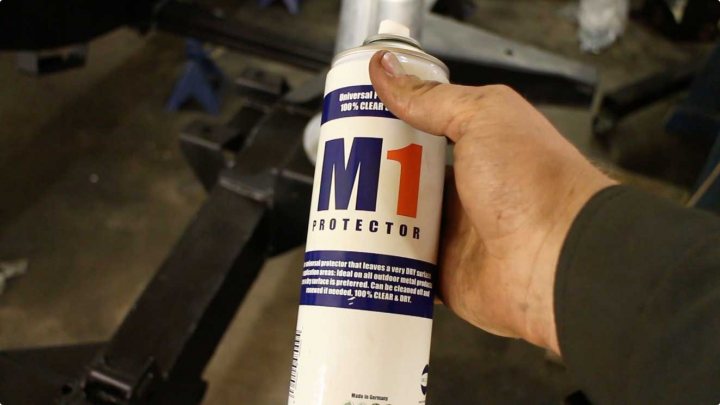 A bottle of beer sitting next to a bottle - Pistonheads - The image shows a close-up of a hand holding a white and blue object with the word "M1" prominently displayed, indicating the model of a product, likely an air compressor. The hand grips the tool a little below the nozzle. The background is slightly out of focus, but it appears to be a workshop or garage setting. There is a blue stripe detailing the compressor's features or specifications.