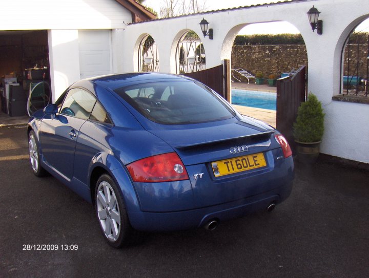 Plates Pistonheads Private - The image showcases a blue Audi TT Coupe parked on a gravel driveway in front of a white building. The car features a distinctive design with a sleek body and a short rear deck, typical of the TT models. This Audi is equipped with a license plate, though the specific details are not visible in the image. In the background, there is an outdoor swimming pool, adding to the leisurely atmosphere of the setting. The timestamp "28/12/2009 13:09" is visible on the image, suggesting that the photograph was taken late in the December of the year 2009.