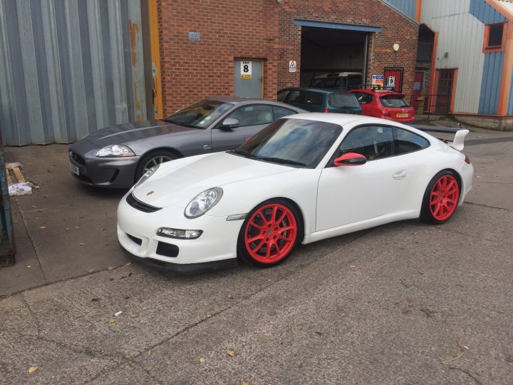 A car is parked on the side of the road - Pistonheads - The image showcases a striking scene in a parking lot. Dominating the foreground is a white Porsche, its body gleaming under the light. It's parked next to a vibrant red Porsche, both of them stationary amidst other cars. 

The backdrop is equally interesting with a brick building standing tall, and a solitary tree swaying in the breeze. The overall composition suggests a casual day out, perhaps after a spirited drive around town.