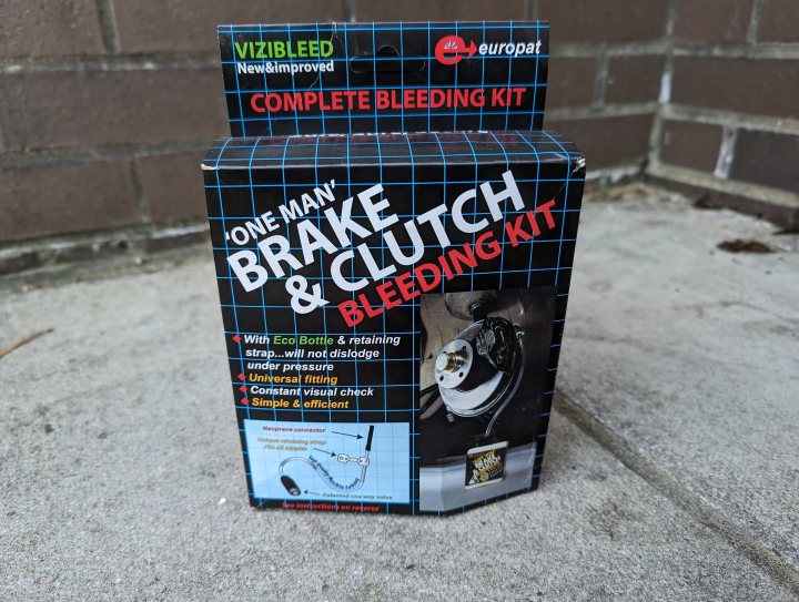 Civic Type R FN2 Track Car  - Page 10 - Readers' Cars - PistonHeads UK - The image shows a small cardboard box with various items. It's labeled "One Man Clutch & Bleeding Kit." The items inside the box include a set of clamps, a tube of fluid, and some wrenches or tools. There are also additional items such as a small bottle and what appears to be a patch or pad. The packaging is placed on a surface that has a blue object, possibly a piece of furniture or decoration, in the background.