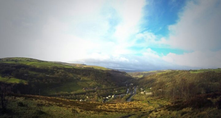 The "Photos From Today's Ride" thread... - Page 113 - Pedal Powered - PistonHeads - The image captures a breathtaking aerial view of a steep valley. The valley is lush and green, filled with trees and vegetation. Nestled within this verdant landscape are quaint houses and fields, their details scarcely visible. Above this picturesque scene, a sprawling cloud formation blankets the sky, adding a sense of serenity and grandeur to the vista below. The perspective of the photo suggests that it was taken from a high vantage point, such as a lookout point or an airplane flying overhead.