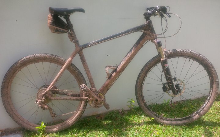 The "Photos From Today's Ride" thread... - Page 150 - Pedal Powered - PistonHeads - The image presents a mountain bike resting against a white wall. The bike, which appears to be in a state of disuse due to rust, has a weathered look. It's leaning against the wall on its kickstand, and a helmet is tied to the handlebars, indicating that it has been momentarily abandoned. The bicycle is quite prominent in the frame, occupying a large portion of the image. The stark contrast between the rusty bike and the white wall behind it emphasizes the age and condition of the bike.