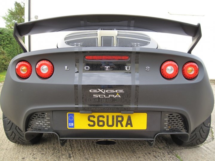 Pistonheads Ive Plate - The image depicts a rear view of a sports car, predominantly black with red taillights. The car's license plate bears the registration number "S6URA", suggesting it could be a luxury or high-performance vehicle. The presence of a spoiler and the design of the taillights suggest a focus on aerodynamics and style. The setting appears to be a paved area with a grassy background, which could indicate the car is outdoors or possibly on display.