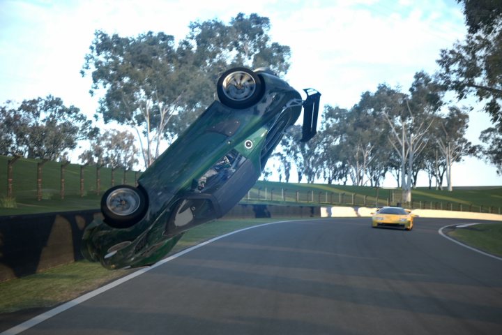 Gran Turismo 6 picture thread - Page 6 - Video Games - PistonHeads - The image showcases a dramatic scene from a video game that appears to depict a car driving on a highway. The car has lost traction and is naturally in mid-air, seemingly performing a cartwheel. The background reveals a grassy area with trees and what appears to be a fence. Another car is visible in the background, passing by the overturned vehicle. The lighting suggests it's a clear day, and the environment seems to be during daytime.