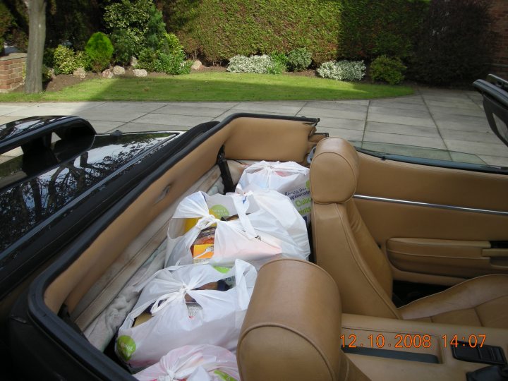 Pistonheads - The image shows the interior of a light-colored SUV. Many shopping bags are filled with groceries and arranged in the trunk area. The bags are tied or strapped securely. There is a brand name visible on the bags, but it is not identifiable. Outside the vehicle, you can see a landscaped garden with trimmed hedges. The scene appears to be taken on a residential street, with a sidewalk visible alongside the parked SUV. The image also contains a timestamp in the corner, indicating it was taken in the year 2008.