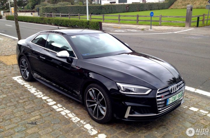 The S5 lease thread - Page 9 - Audi, VW, Seat & Skoda - PistonHeads - The image shows a black Audi sports car parked on a street. The car is positioned at an angle to the camera, allowing a clear view of its front and side profile. It is parked next to a neatly trimmed lawn on the other side of the street. Adjacent to the car, there is a street marking confirming the parking spot. The surrounding environment includes a fence and a tree, indicating a quiet suburban setting.