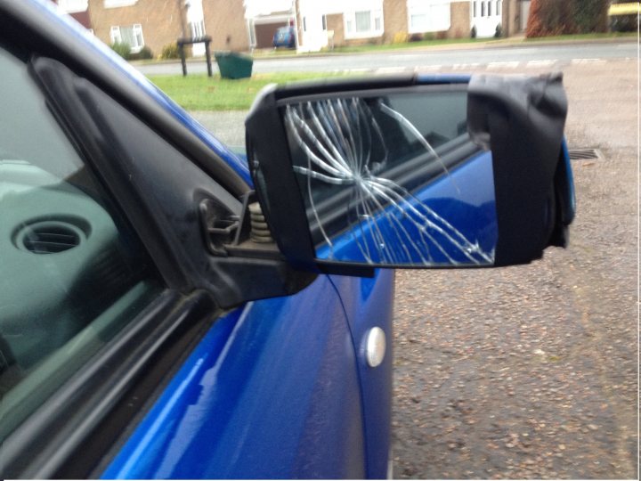 What have I got myself into? - Page 4 - Subaru - PistonHeads - The image shows the side view mirror of a vehicle, reflecting a web of cracks, suggesting recent collision or impact damage. The surrounding environment includes a paved street, a grassy area, and the edge of a house. The mirror itself appears to be tilted or damaged within its frame. The reflection in the mirror adds a unique perspective to the scene.