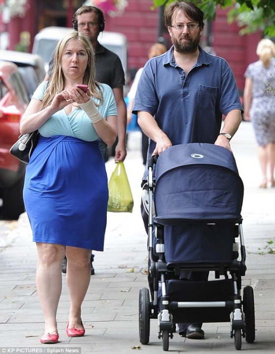 Prof Dr Alice Roberts - Page 2 - TV, Film & Radio - PistonHeads - In the bustling cityscape, a man and a woman stand out as they navigate the sidewalk. The man, dressed casually, is pushing a large blue stroller that he presumably brought with him. The woman, on the other hand, is caught in a moment of connection with the outside world as she checks her phone. 

Behind them, life goes on as other people walk by, engrossed in their own worlds. A car and a truck, symbols of urban life, add to the dynamic city scene. The couple appears to be in mid-stride, suggesting they are moving along the sidewalk at a purposeful pace. The image captures a slice of everyday city life, with its blend of individuality and collective movement.