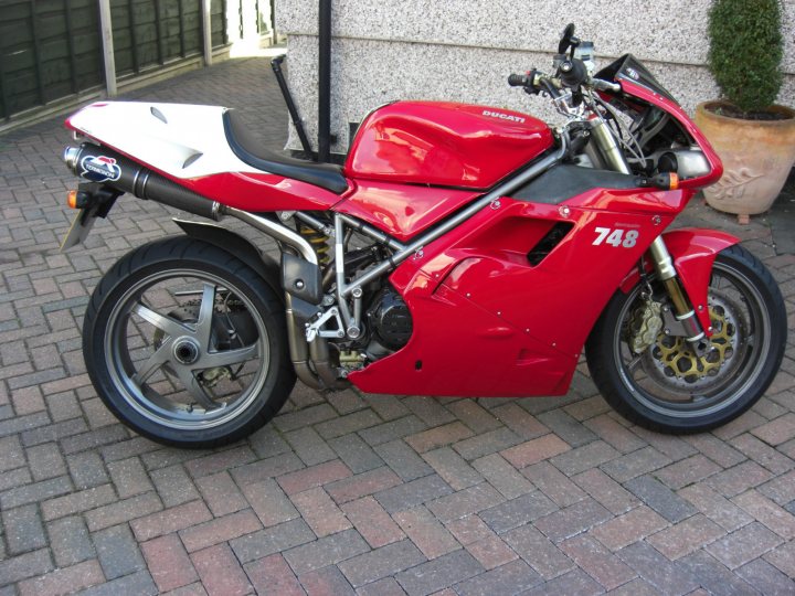 A red motorcycle parked in front of a building - Pistonheads