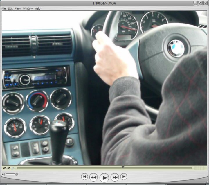 Overboost Pistonheads Vmax Results - The image presents a close-up view from the driver's seat of a BMW car. A hand on the steering wheel is the focal point of the image. The steering wheel is grasping a gear shifter, indicating control over the vehicle. Below the steering wheel, the dashboard is visible, equipped with multiple gauges and dials, characteristic of a BMW's dashboard. The colors in the image are soothing, with the car's interior in shades of gray and turquoise.