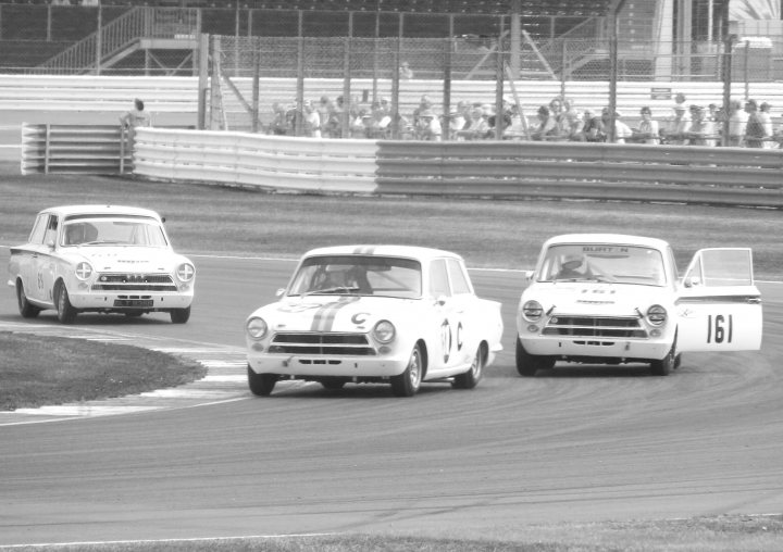 Fantastic Motorsport Photos! - Page 204 - General Motorsport - PistonHeads - In this black and white photograph, a vibrant racing scene is captured in a stadium with bleachers filled with spectators. The focus is on three vintage race cars dominating the track, with numbers 10C, 13, and 16 prominently displayed. The cars appear to be in an active race, emphasizing the speed and excitement inherent in the sport.