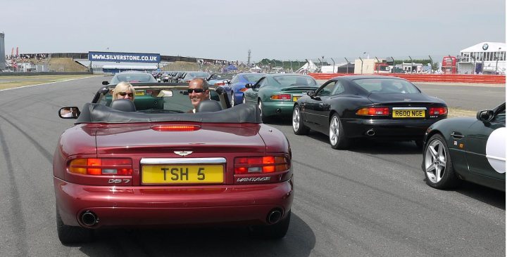 Who's got what in the South West - Page 1 - South West - PistonHeads - The image captures a vibrant scene on a bustling race track. Multiple cars, each with their unique models, are racing down the track. Each car carries the license plate "TSH 5". The drivers, all appearing to be older men with glasses, are intently focused on the race, their expressions one of concentration and determination. The race track itself is wide and open, with the distant buildings and sky forming a spectacular backdrop.