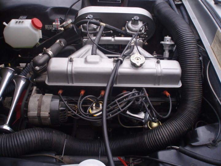 Early TVR Pictures - Page 90 - Classics - PistonHeads - The image presents an up-close view of the engine bay of a vehicle, showcasing the intricate connections of parts. A significant feature is a large air filter attached to the main engine block, which appears to be made of cast iron. Surrounding the main engine block, you can see various wires and hoses, indicating the complexity of the vehicle's electrical and mechanical systems. By focusing on the engine and parts of the vehicle, the image provides a detailed look at the inner workings of this specific model.