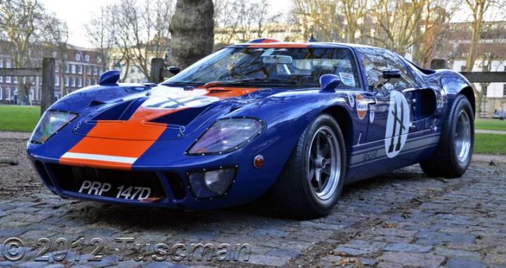 Classics in Queen Square - Page 9 - South West - PistonHeads - The image features a vibrant blue race car parked on a cobblestone street. The car's design is unique, with a mix of red and white stripes, and a prominent white number "3" on the side. The hood of the car is orange and white, giving it a striking appearance. The location appears to be a public space, possibly in a town or city, as indicated by a building partially visible in the background. Overall, the car commands attention with its bold colors and race car design.