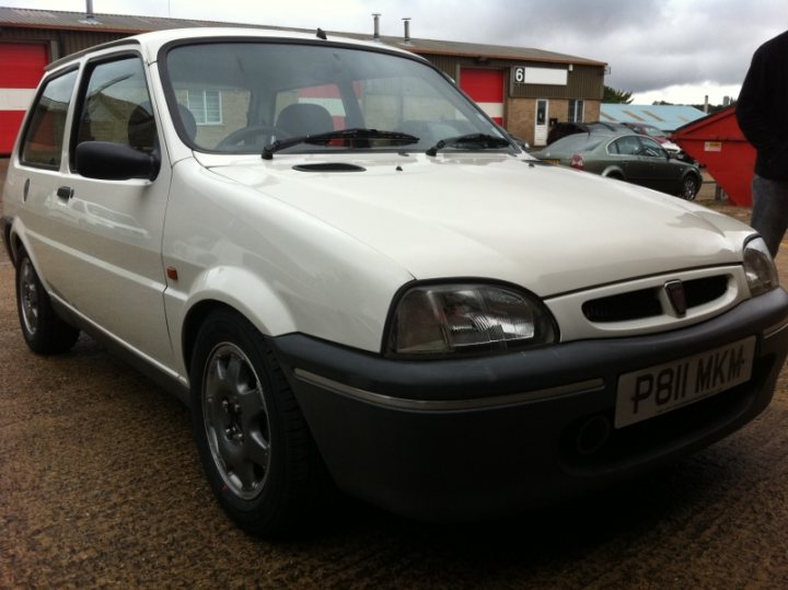 New Car Sneak Preview - Page 1 - East Anglia - PistonHeads - The image displays a small white hatchback parked outside. The car's license plate reads "P81 MKN." The vehicle features alloy wheels and a car receiver is visible on the rear of the vehicle. In the background, a building with red doors and other cars can be seen. The sky is overcast, suggesting an overcast or cloudy day.