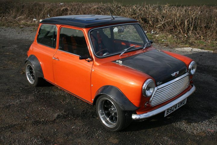 VTEC minis - Page 1 - Classic Minis - PistonHeads - This image captures a vibrant, vintage scene featuring an orange Mini Cooper car. The car, with its black roof and sides, stands out against the backdrop of a rustic setting. The car is positioned on a gravel road, which adds to the rugged charm. One of the notable features of the car is its silver grille, which contrasts beautifully with the orange body. The number plate clearly displays the email address "crtt@freeserve.com". The image beautifully encapsulates the charm and nostalgia associated with vintage automobiles.