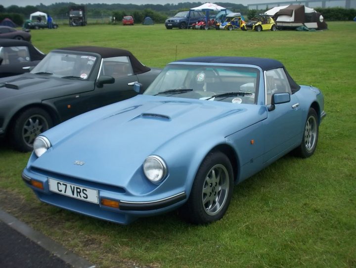 Fave colours - Page 2 - S Series - PistonHeads - The image features a sunny day at what appears to be a car show or meetup. Dominating the scene is a fantastically painted, blue, C-type Jaguar sports car. It's parked in the grass amidst an array of other classic cars, each with their unique aesthetics. The sky is clear, and the field is dotted with small tents and umbrellas, suggesting a relaxed, outdoor event setting. The vibrancy of the colors and the variety of car styles create a lively and interesting atmosphere.