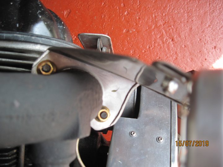 A close up of a black and silver fire hydrant - The image shows a close-up view of a mechanical object, likely part of an engine or machinery. There is visible metalwork with bolts and a clamp, suggesting it's an industrial piece. In the background, there's a red surface which might be a wall, and the focus of the photo is on the object in the foreground. The photograph has a timestamp in the corner, but it's not entirely clear what the timestamp refers to without context.