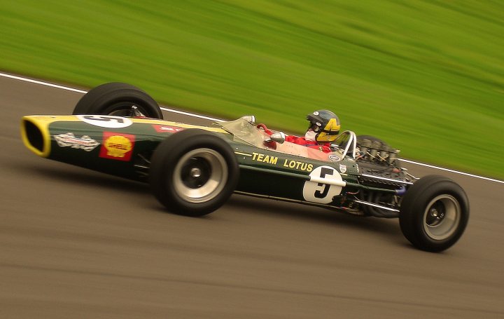 Pistonheads Beautiful - The image captures a moment of high-speed racing on a track. Race car number 5 is prominently displayed on the side of the car. The vehicle, an impressive machine with black and yellow livery, is seen making a left turn, tilted on its right side due to the motion. The frame of the car extends across the width of the track, with the grassy bank visible on one side.