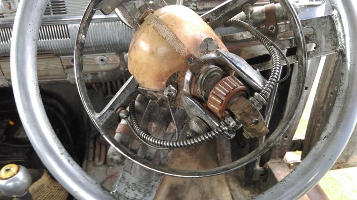 Mad Max Cars on Display - help! - Page 1 - Goodwood Events - PistonHeads - The image shows an interior view of an engine compartment, featuring a close-up of a mechanical component with a complex design. Central to the image is a metal object with various openings, nuts, and bolts, which appears to be a part of a larger machinery, possibly a vehicle. The metallic component is densely packed with elements, suggesting it is a critical component in the engine setup. The surrounding environment exhibits the typical grease and grime associated with engine spaces. The focus is on the detailed structure of the mechanical part, with the background slightly blurred.