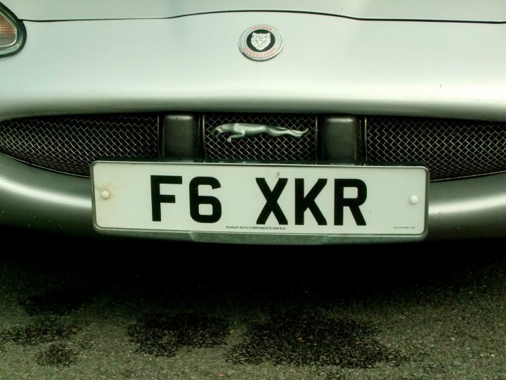 the new wheels !!!! - Page 1 - South West - PistonHeads - The image shows a portion of the front end of a car, focusing on the license plate. The license plate is rectangular, with black lettering and white background, reading "F6 XXR". The car has a manufacturer emblem on the grille, featuring what appears to be a stylized lion's head. The hood of the car is silver and elliptically adorned with a dark circular detail. Beneath the car, water or oil stains can be seen on the asphalt. There are no people present, and the image captures a close-up perspective emphasizing the license plate and the car's front grille. The context of the image is unclear, and it does not provide any additional details about the setting or the specific model of the car.