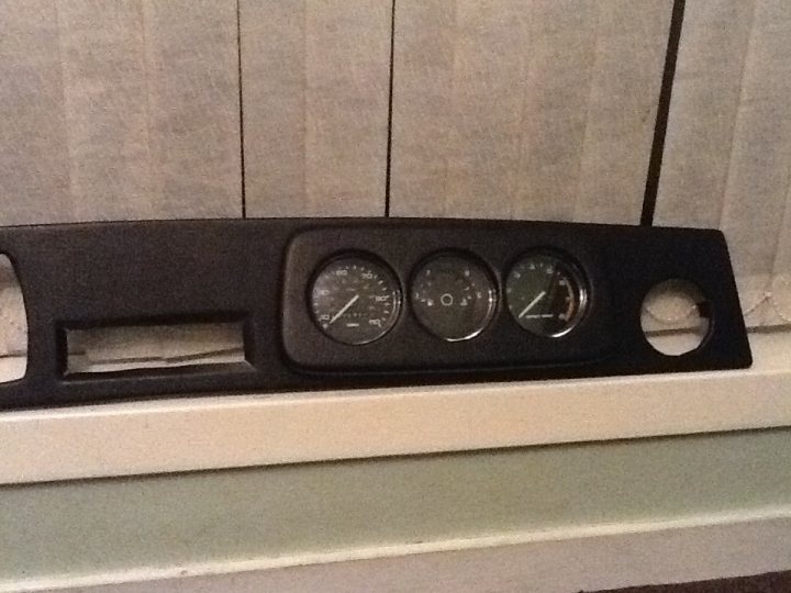 A clock that is on the side of a wall - Pistonheads - The image shows a black automatic clock with a sleek design, likely made of metal or plastic. The clock is positioned on a white mantelpiece. It features a digital display alongside a series of circular buttons on the bottom. The display is lit up with the time reading "09:55". The setting appears to be indoors, possibly within a home, as suggested by the window blinds in the background.