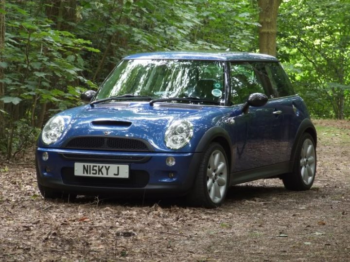 Pistonheads - The image shows a compact blue Mini Cooper parked on a forest path with trees and shrubbery in the background. The car has a clear view through its front windows and license plate visible at the front. The Mini Cooper appears to be a four-door model, and the impression is of a well-maintained vehicle. The scene suggests a peaceful and natural setting, likely in the woods or a rural area, where the car is facing towards the camera, with a clear path ahead.