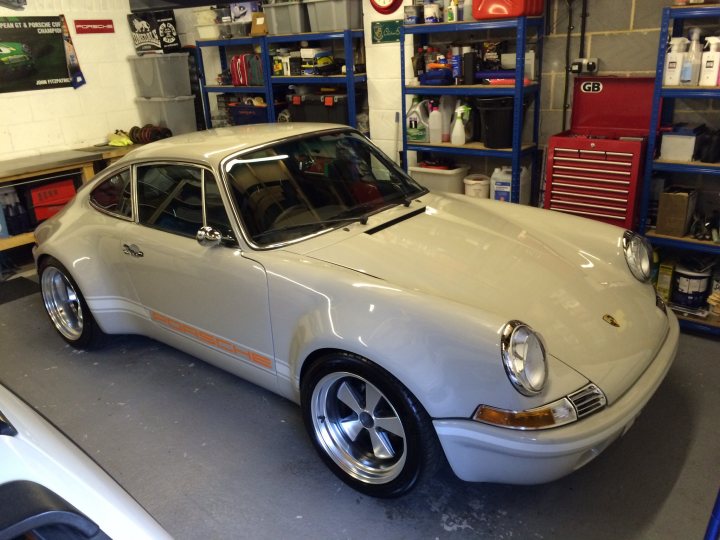 Happy Christmas! - Page 1 - East Anglia - PistonHeads - The image shows a classic, cream-colored Porsche 911 in a garage setting. The car is parked, facing towards the right side of the image, and occupies a substantial part of the frame. The seat and steering wheel of the car are visible, and the overall condition of the car appears to be well-maintained, suggesting it may be a vintage model. In the background, we can see garage shelves holding various items, contributing to the indoor, workshop-like environment. The lighting and perspective suggest that the photograph was taken from a slightly elevated angle, providing a good view of the car's front and side profile.