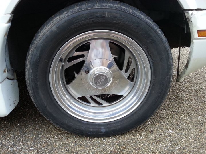 A black and white cat sitting on top of a car - Pistonheads - The image focuses on a single, small car that is predominantly white in color. The car's most striking feature is its silver-colored wheel, which has a five-spoke design and a hubcap with a deep, concave central opening. The hubcap displays a logo, suggesting a particular brand or model of the wheel. The tire mounted on the wheel is black and appears to be relatively new, given the lack of significant wear or tread currently visible. The exterior of the other parts of the car is visible, indicating minor damage to the bumper area, but the rest of the vehicle appears to be in good condition. The photo provides a close-up of the wheel and the edge of the bumper, emphasizing the hubcap and the tire's condition.