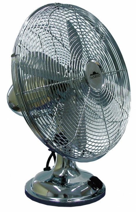 Banco Mutuo Soccorso Del Pistonheads - The image shows a vintage-looking electric rotary fan. It has a characteristic design with a metallic body, a round face characterized by a series of slits resembling tree branches or rays, and serrated or slotted side panels. The central hub is flat, and there is a visible but indistinguishable logo or brand mark on the front. The fan appears to be stationary with no implied movement. The image is a product photo with a clear, neutral background, focusing on the fan and presented in an up-close manner.