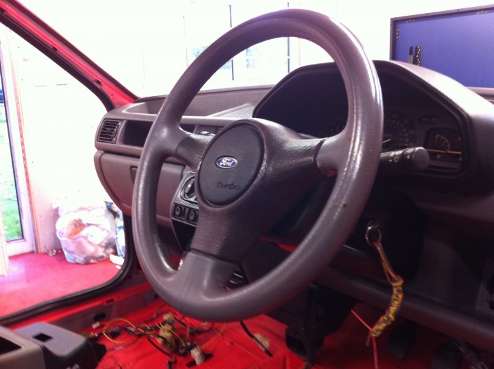 Pistonheads - The image showcases an interior view of a vehicle, specifically focusing on the driver's side. A Ford steering wheel, prominently displaying the Ford logo, is positioned in the center of the frame.