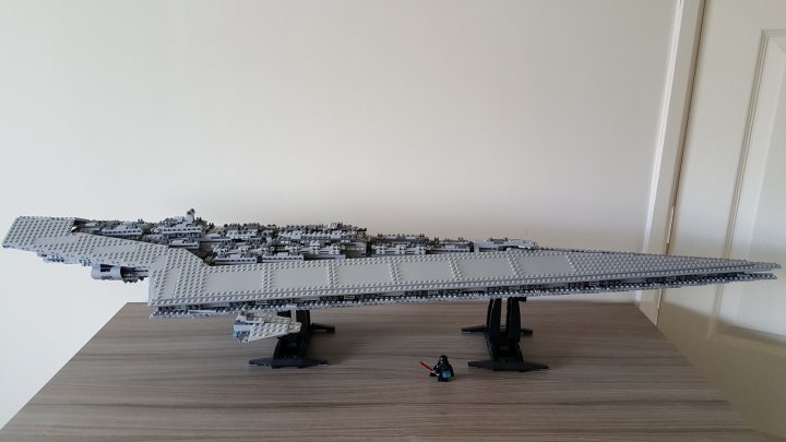 A large jetliner sitting on top of an airport tarmac - The image features a Lego Star Wars model of the Death Star, a famous spacecraft from the Star Wars franchise. The model is on display atop a box, resting on its black base plates that resemble the concrete of a model vs a LEGO structure. A minifigure stands in the foreground, providing a sense of scale to the model behind it. The overall image gives the impression of an organized and meticulous Lego exhibition.