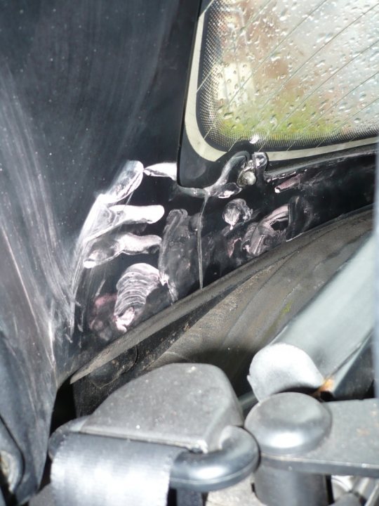 Bodyshop Pistonheads Booked - This image captures a close-up view of a black car door. The door is covered in a thick black substance, possibly paint or a protective coating, and there is a clear smear on it. Additionally, several white splatters are scattered across the door's surface, alongside some white powder or paint chips that have fallen off the door. The overall scene suggests this might be the aftermath of a car accident where paint or cosmetic damage has occurred, and the door is in need of cleaning and repair before further use.