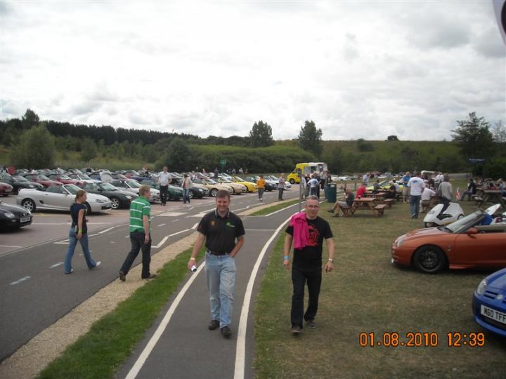 Pistonheads - This image captures a bustling scene of a parking lot filled with many cars. People are seen walking through the lot, with some also strolling on a paved walkway. The setting appears to be a cloudy day, with the area being vast and open, spacious enough to accommodate a large number of vehicles. There is a timestam in the bottom right corner of the image, but no identifiable individuals or distinguishing landmarks are visible.