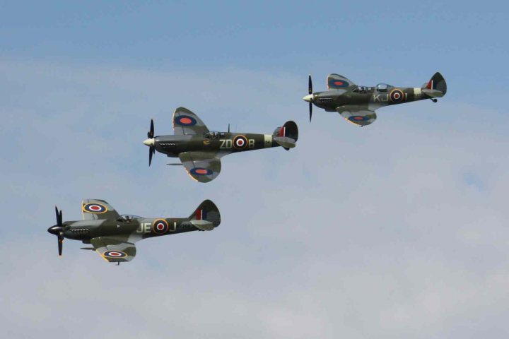 Revival images - Friday  - Page 1 - Goodwood Events - PistonHeads - The image shows four fighter planes flying in formation against a backdrop of a partly cloudy sky. Each plane is painted in a gray color with red, white, and blue markings, and two of them have "ZO" written on their sides. All of the planes feature two spinning propellers and are captured at varying angles, indicating they are in motion. The overall style of the image is a photograph with a focus on the aircraft.