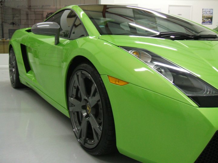 my detailed mistress pics - VI gallardo - Page 1 - Gallardo/Huracan - PistonHeads - The image features a vibrant lime green Lamborghini sports car parked inside a building, likely a showroom or garage. The car is showcasing its sleek design with a hardtop roof, and the lighting highlights the reflective chrome accents and the smooth, impalpable finish of the vehicle. The Lamborghini badge is prominently displayed on the front element of the car. The background is minimal and does not distract from the vehicle, which occupies most of the space in the image. The photo focuses on the car's side and front profile, providing a 3/4 view that emphasizes the vehicle's streamlined design and the curve of the hood.