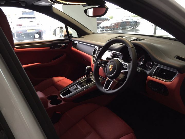 Macan 2ltr petrol - Page 1 - Front Engined Porsches - PistonHeads - This image shows the interior of a luxury car from the driver's seat. The car's interior is adorned with high-end materials such as leather and suede, with the seats being a vibrant red color. The steering wheel and center console of the car are black, providing a striking contrast to the red upholstery. The car has a modern dashboard and a variety of controls and buttons on the center console. The car's digital display is visible, showing various information pertinent to the vehicle's status.