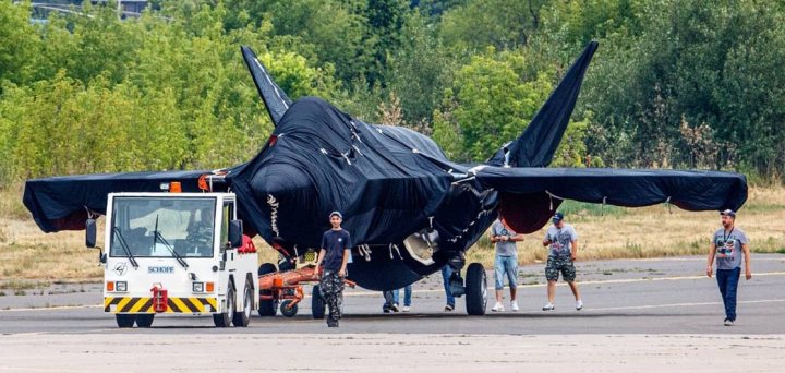 What will the Government buy if the F35 is cancelled? - Page 79 - Boats, Planes & Trains - PistonHeads UK - The image shows a large military-style jet parked on an airport tarmac. The jet is black and appears to be in good condition. There are several people around the aircraft, some of whom are standing close to it while others are further away. A truck with its cargo door open is positioned next to the jet, suggesting that some work or preparation might be underway. The setting is clear, indicating good weather conditions at the time the photo was taken.